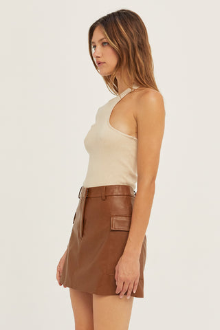 A woman wearing a bone one shoulder cut out sweater top.