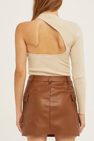 A woman wearing a bone one shoulder cut out sweater top.