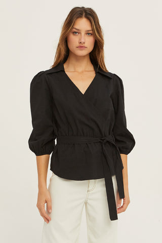 A woman wearing a black tencel wrap top.