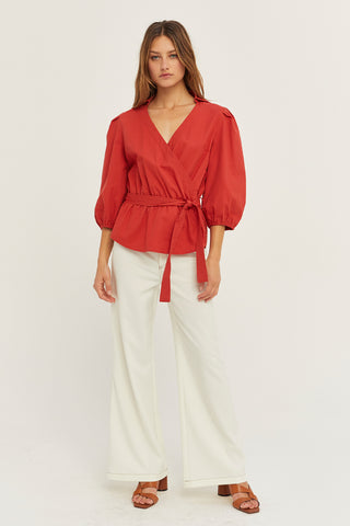 A woman wearing a brick tencel wrap top.
