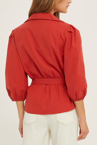 A woman wearing a brick tencel wrap top.