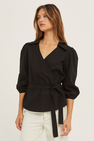 A woman wearing a black tencel wrap top.