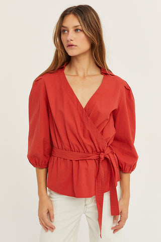 A woman wearing a brick tencel wrap top.