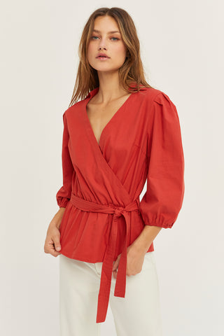A woman wearing a brick tencel wrap top.