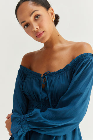 A woman wearing a blue baby doll long sleeve top.