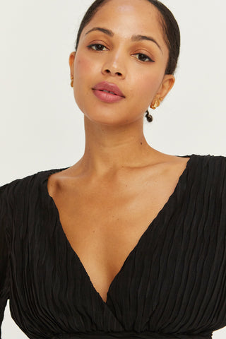A model wearing a black crinkled blouse.