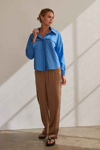 A model wearing a blue button up utility blouse.