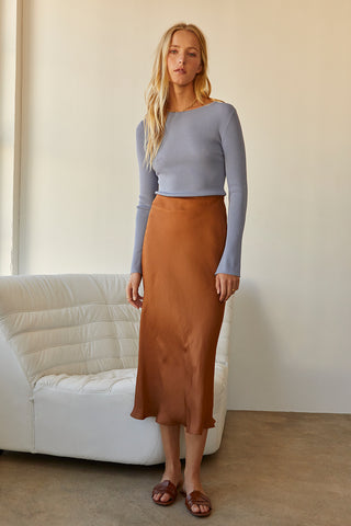 A model wearing a dusty blue long sleeve knit top with slit detail on sleeve.