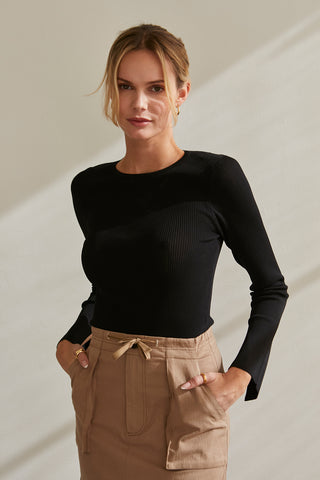 A model wearing a black long sleeve knit top with slit detail on sleeve.