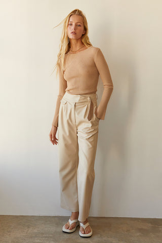 A model wearing a taupe long sleeve knit top with slit detail on sleeve.