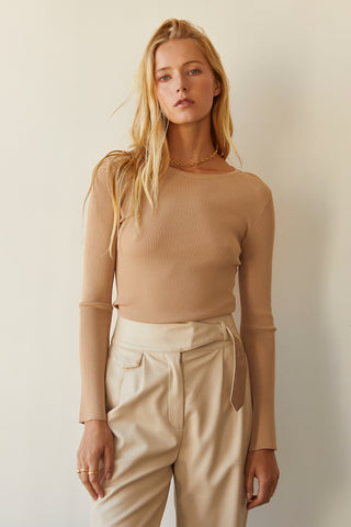 A model wearing a taupe long sleeve knit top with slit detail on sleeve.