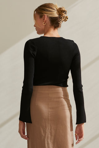 A model wearing a black long sleeve knit top with slit detail on sleeve.