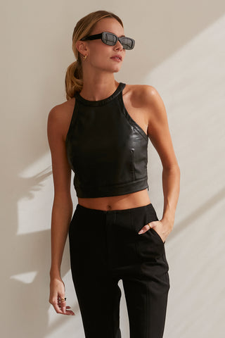A model wearing a black vegan leather cropped halter neck top.