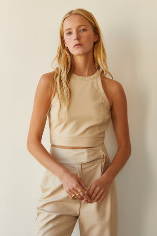 A model wearing a bone vegan leather cropped halter neck top.