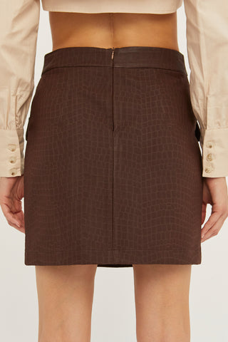 A model wearing a brown embossed vegan leather mini skirt.