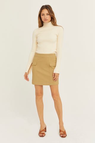 A model wearing a tan embossed vegan leather mini skirt.