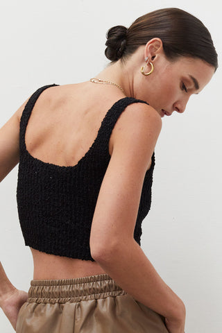 A woman wearing a black knitted tank top.