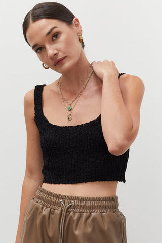 A woman wearing a black knitted tank top.