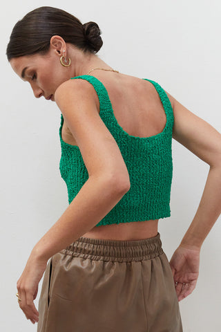 A woman wearing an emerald knitted tank top.