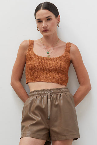 A woman wearing a rust knitted tank top.