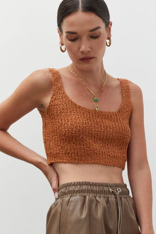 A woman wearing a rust knitted tank top.