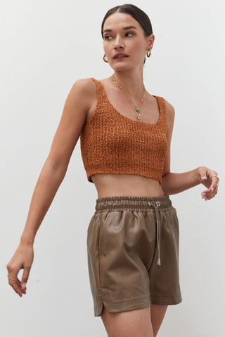 A woman wearing a rust knitted tank top.