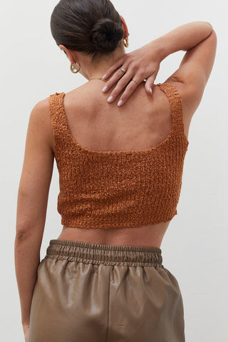 A woman wearing a rust knitted tank top.