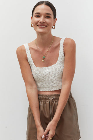 A woman wearing an ivory knitted tank top.