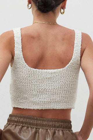 A woman wearing an ivory knitted tank top.