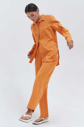 A woman wearing a orange cotton linen blend shirt and pants set.