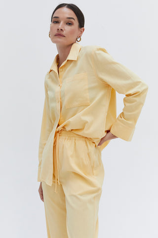 A woman wearing a light yellow cotton linen blend shirt and pants set.