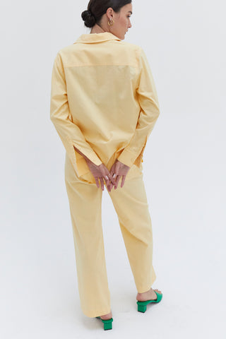 A woman wearing a light yellow cotton linen blend shirt and pants set.