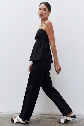 A woman wearing a black pleated babydoll camisole set.