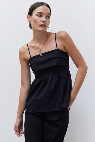 A woman wearing a black pleated babydoll camisole set.