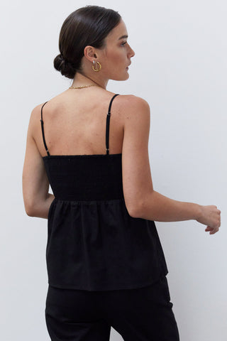 A woman wearing a black pleated babydoll camisole set.