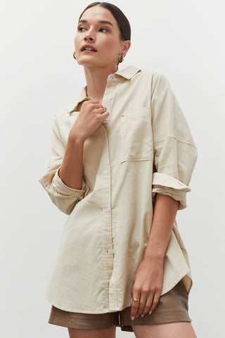 A woman wearing a beige corduroy oversized shirt.