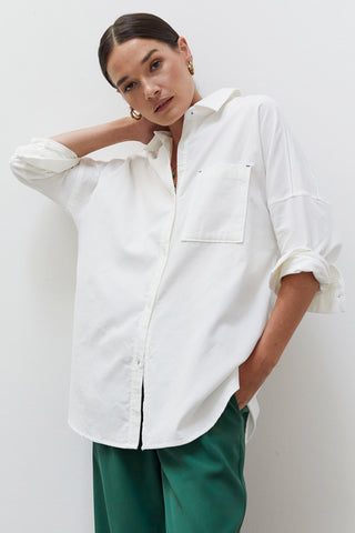 A woman wearing a white corduroy oversized shirt.