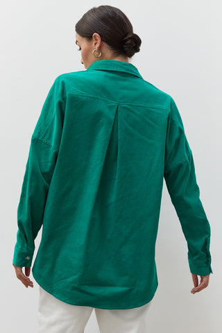 A woman wearing an emerald corduroy oversized shirt.