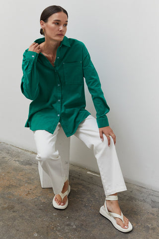 A woman wearing an emerald corduroy oversized shirt.