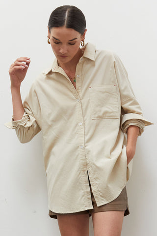 A woman wearing a beige corduroy oversized shirt.