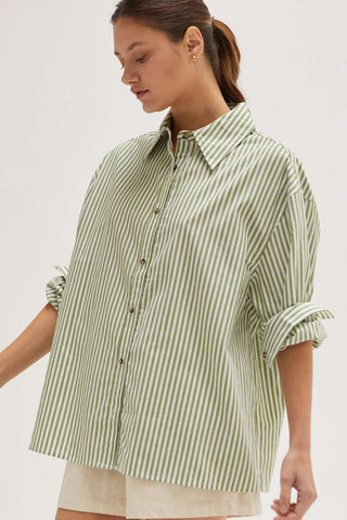 A woman wearing a light green stripe oversized shirt.
