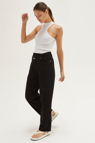 A woman wearing a black straight-leg asymmetric waist jean.