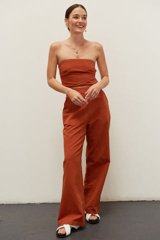 A woman wearing a brick linen bandeau two piece set.