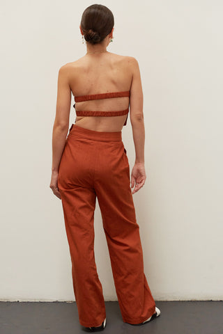 A woman wearing a brick linen bandeau two piece set.