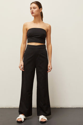 A woman wearing a black linen bandeau two piece set.