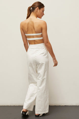 A woman wearing an ivory linen bandeau two piece set.