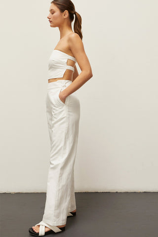 A woman wearing an ivory linen bandeau two piece set.