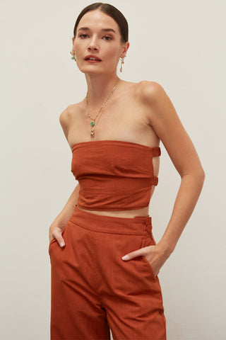 A woman wearing a brick linen bandeau two piece set.