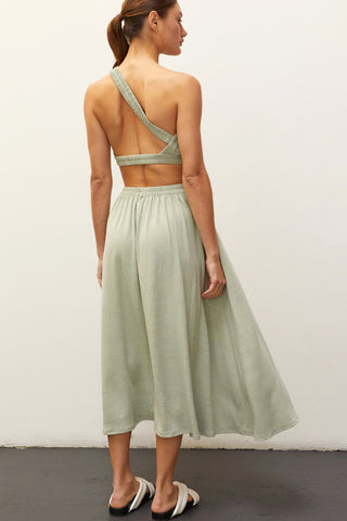 A woman wearing a sage one shoulder two piece set.