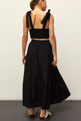 A woman wearing a black bow tie top two piece set.
